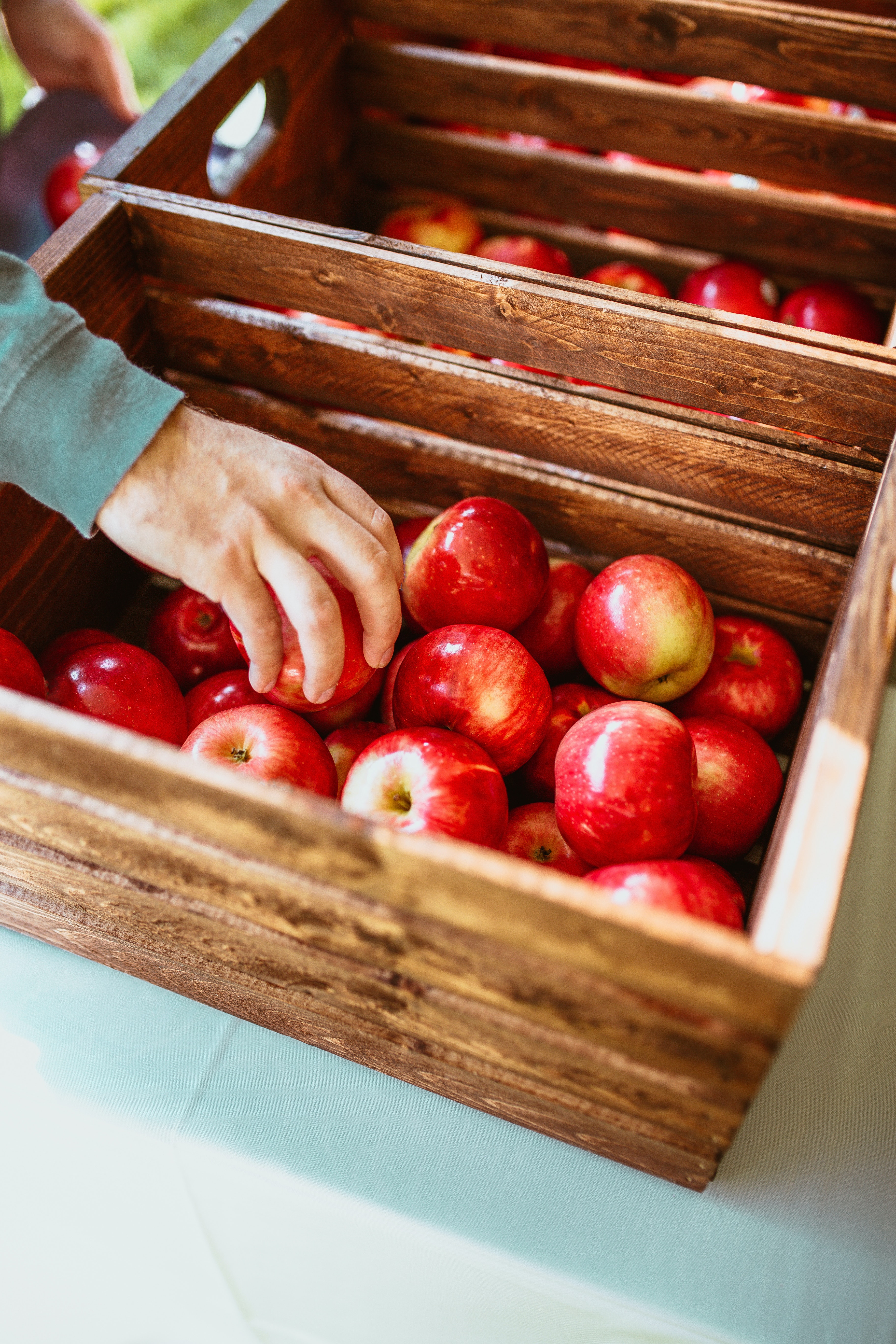 Man reaching for an apple in a basket.